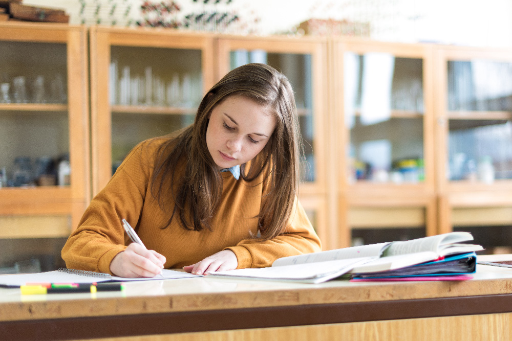 Young female college student in chemistry class, writing notes. Focused student in classroom. Authentic Education concept. Young female college student in chemistry class, writing notes. Focused student in classroom. Authentic Education concept.